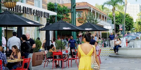 Photograph of a women in yellow walking outside of the Little Italy Food Hall