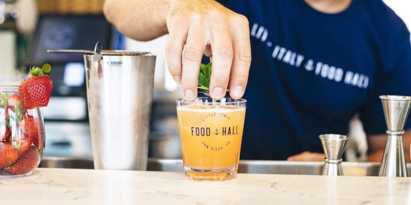 Bartender completing the cocktail with a mint and cucumber garnish