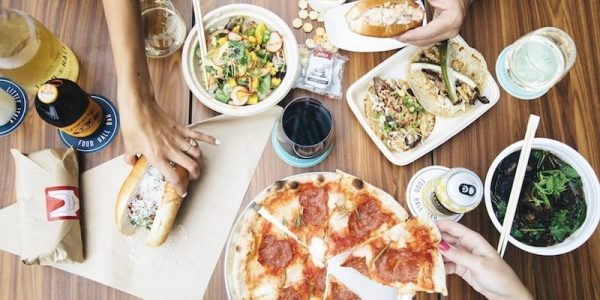 Bird's eye photograph of dishes from all the Little Italy Food Hall vendors which includes a pizza, tacos, lobster roll and meatball sub