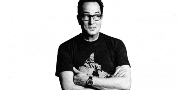 Black and white photo of Sam the Cooking Guy smirking and looking away from the camera