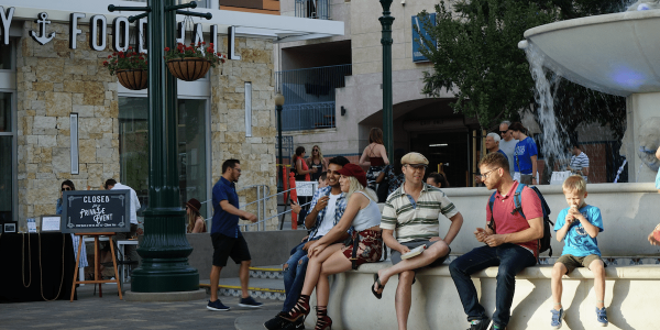 Exterior shot at Little Italy Food Hall of people enjoying food in the Piaza